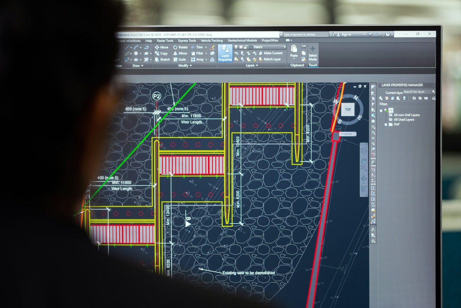 Engineer reviewing technical design drawings using AutoCAD for petroleum engineering project planning