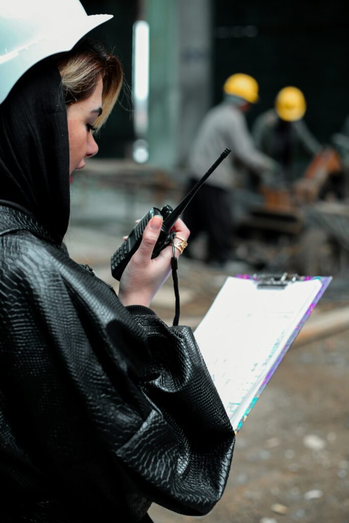 Telecommunications officer using a handheld radio to coordinate communication operations at an industrial site.
